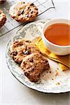 Cranberry oat breakfast cookies on a decorative plate with a cup of herbal tea