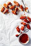 Chicken wings coated with two different sauces on white parchment paper with spoon and brush