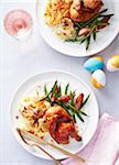 Two plates with cornish hens, scallop potatoes and green beans for Easter dinner