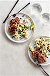 Two plates of grilled lamb chops with cauliflower salad on a grey background