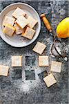 Bowl of lemon squares with icing sugar on a grey metallic background