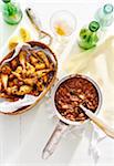 Baked beans in a cooking pot with deep fried okra in a basket and bottles of beer