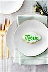 Sugar cookie place card with name in icing on a dinner plate in a festive place setting