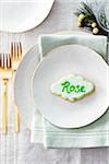 Sugar cookie place card with name in icing on a dinner plate in a festive place setting