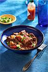 Texas style chili in a blue bowl with a fork on a blue background