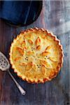 Tourtiere with a decorated crust on a blue wooden background