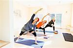 Three women practicing extended side angle lunge, (parsvakonasana) yoga pose in yoga studio