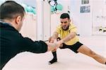 Men in gym doing stretching exercises