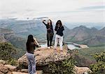 Three young female tourists looking out and taking selfie from The Three Rondavels, Mpumalanga, South Africa