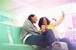 Two mid adult women taking selfie in airport departure lounge