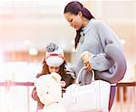 Girl with teddy bear and mother in airport departure lounge