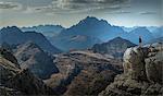 Climber on cliff looking at mountain ranges, Dolomites, Cortina d'Ampezzo, Veneto, Italy