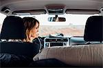 Young woman driving vehicle in remote setting, rear view, vehicle interior, Mexican Hat, Utah, USA