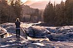 Young woman outdoors, looking at rural surroundings, rear view, Vancouver Island, Canada