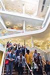 Business people descending stairs in modern lobby atrium