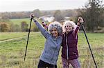 Portrait enthusiastic, confident active senior women friends hiking with poles in rural field