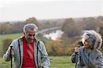 Active senior couple hiking with poles in park