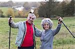 Portrait enthusiastic, confident active senior couple hiking with poles in rural field