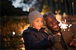 Grandfather and curious grandson playing with firework sparklers