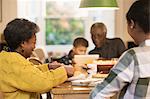 Family eating and using digital tablet at dining table