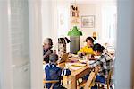 Grandparents at dining table with grandchildren doing homework,