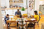 Grandparents at dining table with grandchildren doing homework