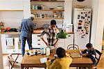 Grandparents and grandchildren baking and using digital tablet in kitchen