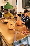 Family carving Halloween pumpkins at dining table