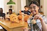 Portrait smiling, confident teenage girl holding painted Halloween pumpkin ceramic