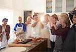 Chef and active senior friends clapping in pizza cooking class