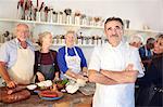 Portrait confident chef with senior students in cooking class kitchen