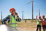 Smiling engineer talking on cell phone at sunny wind turbine power plant