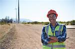 Portrait smiling engineer on dirt road at wind turbine power plant