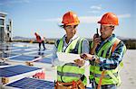 Engineers using walkie-talkie and digital tablet at solar power plant