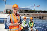 Portrait smiling, confident female engineer with walkie-talkie at sunny solar power plant