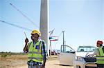 Male engineer with walkie-talkie at sunny wind turbine power plant