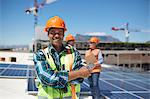 Portrait confident engineer installing solar panels on sunny rooftop