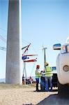 Engineers meeting at truck at sunny wind turbine power plant