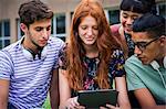 Group of college students looking at digital tablet together outdoors