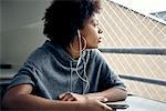 Young woman listening to earphones and gazing out window