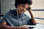 Young woman using smartphone and earphones, smiling, portrait