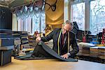 Tailor examining roll of cloth in tailor shop