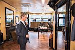 Male customer in full suit looking at mirror in tailors shop