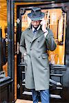 Cool male customer wearing trilby outside tailors shop, portrait