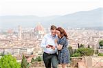 Young couple smiling at mobile phone, Santa Maria del Fiore in background, Florence, Toscana, Italy