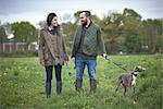 Woman and man walking dog in field