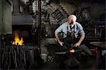 Blacksmith hammering red hot metal in blacksmiths shop