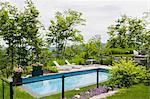 Sun loungers by outdoor swimming pool in residential backyard