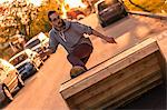 Young male skateboarder turning moving up ramp on suburban street at sunset