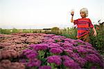 Blond haired boy in garden looking down at pink and purple flowers